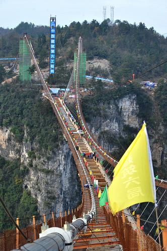 施工中的张家界大峡谷玻璃桥（12月3日摄）。12月3日，随着最后一片重达41吨加劲梁的精准吊装，湖南张家界大峡谷玻璃桥钢箱梁成功合龙。据悉，张家界大峡谷玻璃桥总长430米、宽6米，桥面距离谷底相对高度约300米。桥面全部采用透明玻璃铺设，最大游客容量为800人。目前，大桥建设进入施工尾期，预计2016年“五一”节前对外开放。新华社记者 龙弘涛 摄